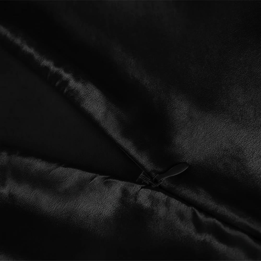 Taie d'oreiller en soie noire avec une texture lisse et brillante, fermée par une petite fermeture éclair