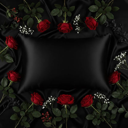 Taie d'oreiller en soie noire entourée de roses rouges et de feuillage vert sur un fond sombre