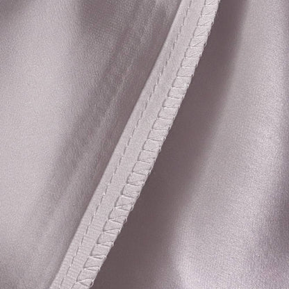 Détail d'une taie d'oreiller en soie de mûrier lilas avec couture soignée et texture lisse