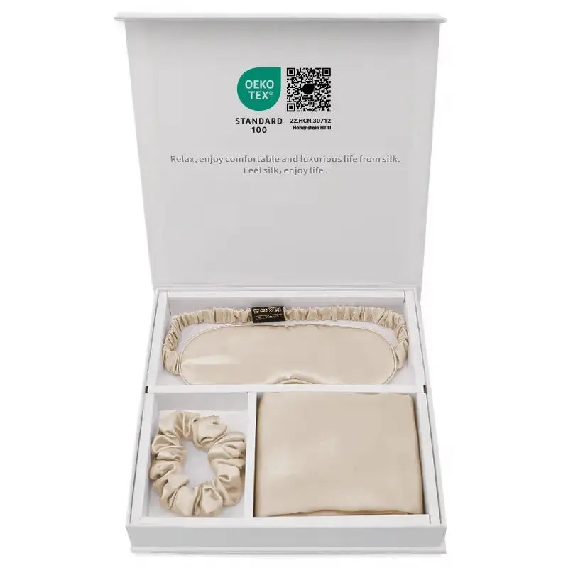 Coffret cadeau en soie contenant une taie, un masque et un chouchou beige dans une boîte élégante