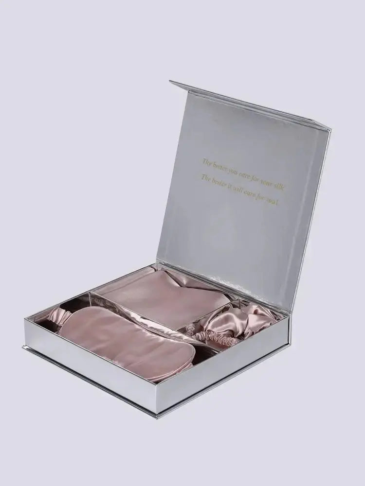 Coffret cadeau ouvert contenant une taie, un masque et un chouchou en soie rose poudré